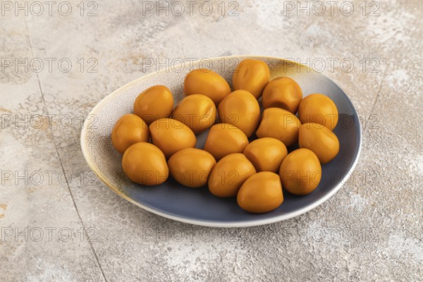 Pile of Smoked Quail eggs on plate on a brown concrete background. side view, close up
