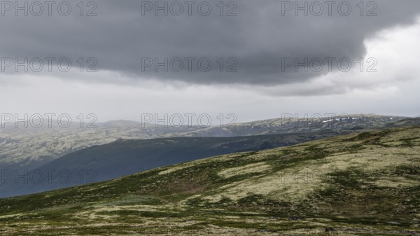 Vast mountain landscape with patches of snow and a cloudy atmosphere, pilgrimage route Olavsweg or Olavsleden, old Kongevegen or King's Path over Dovrefjell, Norway