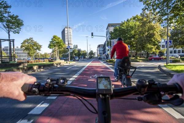 Riding a bike in a bike lane, marked in red to attract the attention of motorists, between 2 lanes, Huyssenallee, in front of Europaplatz, in the city centre of Essen, North Rhine-Westphalia, Germany