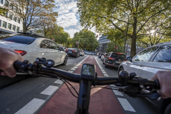 Riding a bike in a bike lane, marked in red to make drivers aware of the bike lane, between 2 lanes, Huyssenallee, in the city centre of Essen, North Rhine-Westphalia, Germany