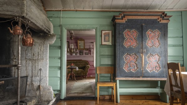 Raum mit großem alten Kamin, einem bemalten Bauernschrank und grüner Holzwand, historischer Bauernhof und Pilgerunterkunft Budsjord, Dovre, Pilgerweg Olavsweg oder Olavsleden, Gudbrandsdalen oder Gudbrandstal, Norwegen