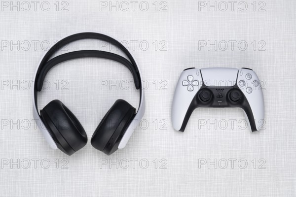Top shot of a Playstation 5 headset and a game controller on a white Resopal board