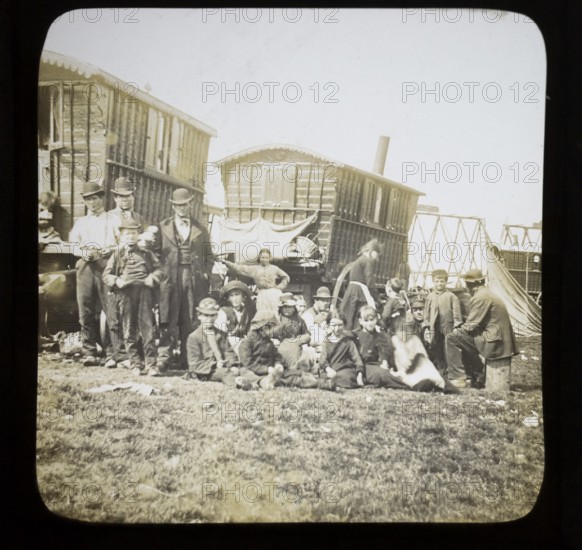 Magic lantern slide portrait of fairground travelling gypsy extended family and caravans, UK circa 1900