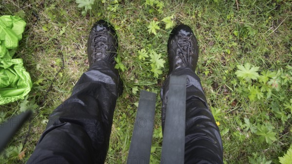 Blick auf nasse Wanderschuhe, Wanderhose und Gras von oben, regnerisches Wetter, Pilgerweg Olavsweg, Olavsleden oder Pilgrimsleden, Dovrefjell, Norwegen