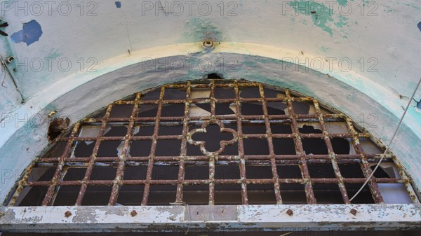 Lost Place, Rostiges Gitter an einem kaputten Fenster mit verblassten Wänden, Caserma Avieri, Gefängnis, Konzentrationslager, Psychiatrische Klinik, Irrenanstalt, Lakki, Leros, Dodekanes, Griechische Inseln, Griechenland