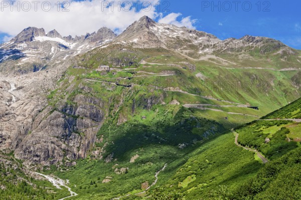 View of Furka pass road Alpine pass with tight bends hairpin bends on steep mountain slope above tree line in summer, centre top pass summit of Furka pass, Canton Valais, Switzerland