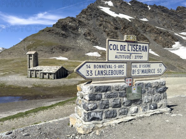 In the foreground signpost to the pass summit of the highest passable 2764 2770 metre high Alpine pass Col de l'Iseran Iseranpass, Iseran, below direction signs to Lanslebourg and Bourg Saint Maurice, in the background mountain chapel Chapelle Notre-Dame-de-Toute-Prudence, Col de l' Iseran, departmental road D902, Route des Grandes Alpes, Département Savoie, Region Auvergne-Rhône-Alpes, Graian Alps, France