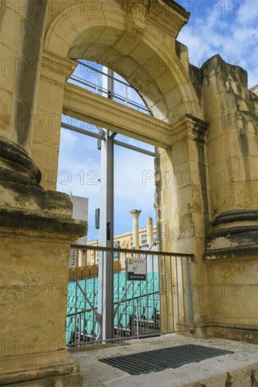 View through former arched window of ruins of former opera house Royal Opera House of Valletta destroyed in World War II on seating of integrated open-air stage, Valletta, Malta