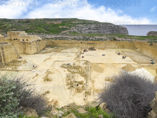 View from above into sandstone sand-lime brick quarry, in the background vertically cut quarried rock, in the centre of the picture lorry for transport, Gozo, Malta