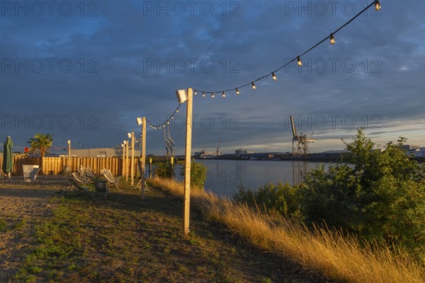 View from the outside area of a restaurant at Lankenauer Höft through a string of lights onto Neustadt harbour in the evening light, Weser, Bremen, Germany