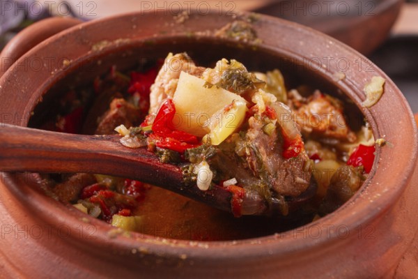Chanakhi, a Georgian dish. in a clay pot, on a wooden table, stewed meat with vegetables, homemade, no people