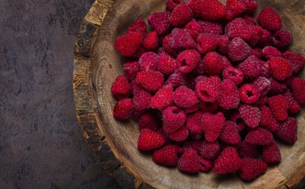 Fresh raspberries in a wooden bowl, food background, concept, food styling, on a dark table, top view, no people