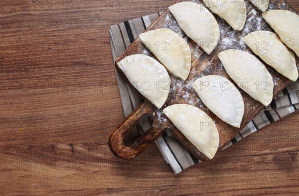 Traditional Polish dish, dumplings, raw, frozen, on a cutting board, wooden table, top view, no people