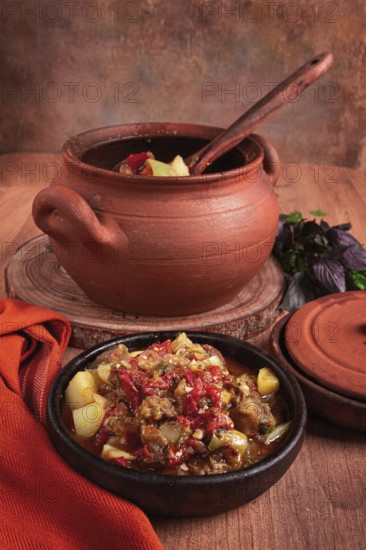 Chanakhi, a Georgian dish. in a clay pot, on a wooden table, stewed meat with vegetables, homemade, no people