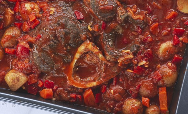 Ossobuco stew with vegetables, knuckle on the bone with new potatoes, in tomato sauce, homemade, top view, no people