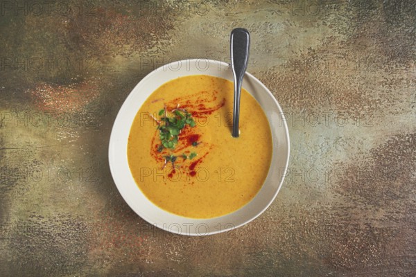 Pumpkin cream soup, in a white bowl on a textured background, top view, homemade, no people, rustic style
