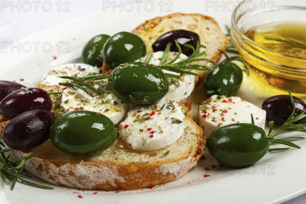A plate with a snack, ciabatta bread with cheese and olives, olive oil, spices and herbs, top view, no people