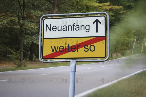 (Photomontage) An exit sign in front of a country road points in the direction of NEUANFANG and leaves WEITER SO