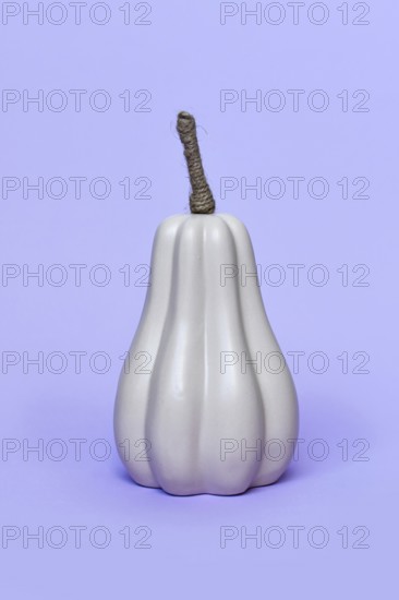Single grey ceramic pumpkin ornament on purple background. Minimal autumn decoration object