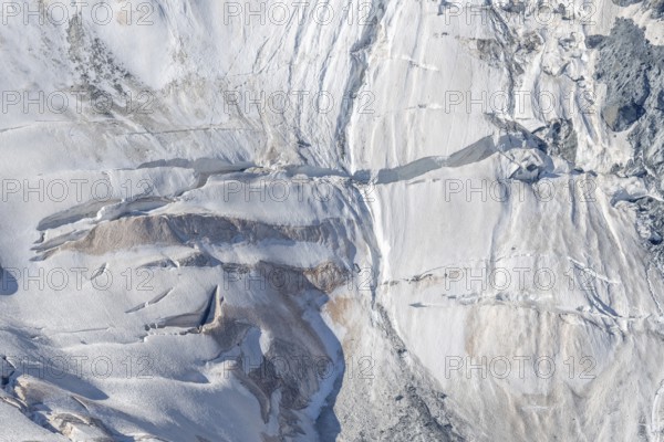 Intricate patterns of ice and rock are showcased in this stunning glacial landscape, revealing the effects of time on the frozen surface. The bright daylight emphasises the textures and colours. Gorner Glacier, Zermatt, Valais, Alps, Swiss