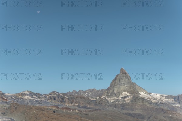 The iconic Matterhorn stands high above a clear evening sky illuminated by a bright moon. This breathtaking view captures the beauty and serenity of the Swiss Alps near Zermatt. Valais, Alps, Switzerland