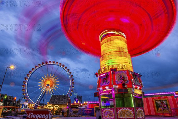 Illuminated chain carousel in motion, behind the Ferris wheel at standstill, Festwiese, Theresienwiese, Oktoberfest, Munich, Upper Bavaria, Bavaria, Germany