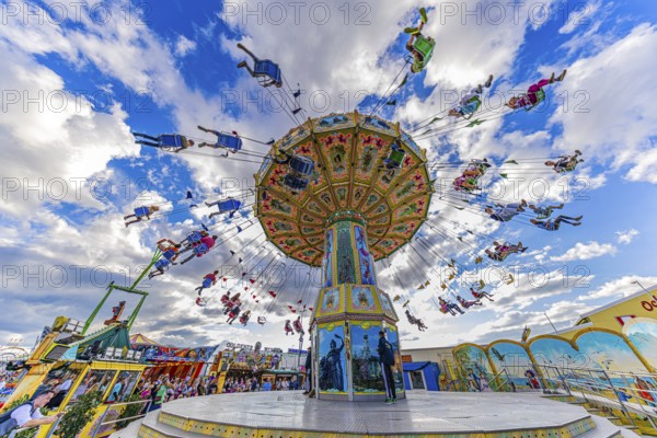 Chain carousel in motion in front of a white-blue sky, Theresienwiese, Oktoberfest, Munich, Upper Bavaria, Bavaria, Germany
