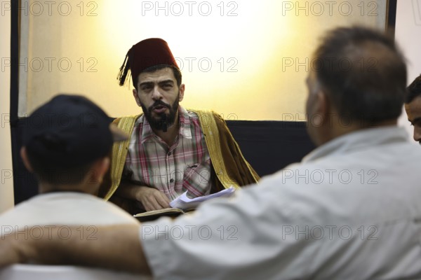 A Syrian puppeteer entertains children at the Damascus International Fair by imitating the role of the Hakawati, a traditional storyteller, while using hand puppets. The performance reflects Syria's cultural heritage and was part of activities organized for young visitors, Damascus, Damascus, Syria