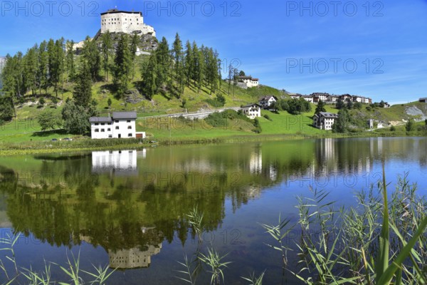 Tarasp Castle in the Lower Engadine is reflected in Lake Tarasp, Graubünden, Switzerland