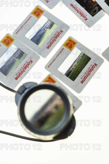 Many framed Kodachrome slides on a light table with magnifying glass, top shot