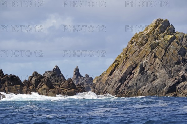 Rock formations by the sea with undulating water and cloudy sky, Isles of Scilly, Cornwall, Great Britain