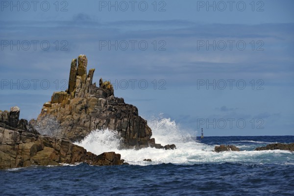 Rough sea with waves crashing against rocks under a blue sky, Isles of Scilly, Cornwall, Great Britain