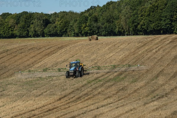 Tractor spreading fertilizer on harvested stubble field in Ystad municipality, Skåne county, Sweden, Scandinavia
