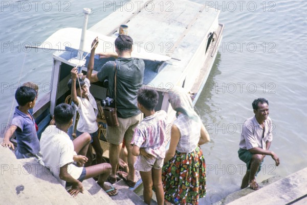 Picnic party embarking on boat for the islands, East coast, Mersing, Johor, Malaya, Malaysia, south east Asia 1964