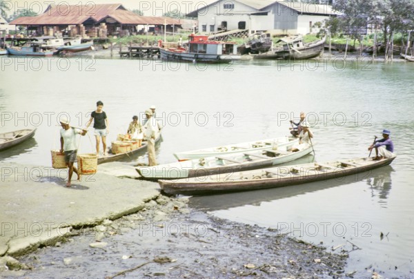 Canoes bringing fish to market, ice and fish packing factories, East coast, Mersing, Johor, Malaya, Malaysia, south east Asia 1964