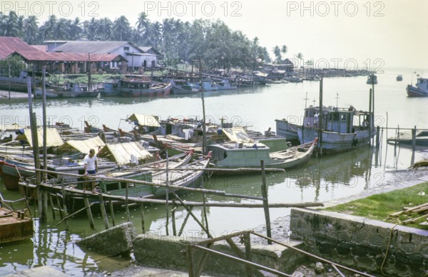 Boast moored on River merging at its mouth, East coast, Mersing, Johor, Malaya, Malaysia, south east Asia 1964