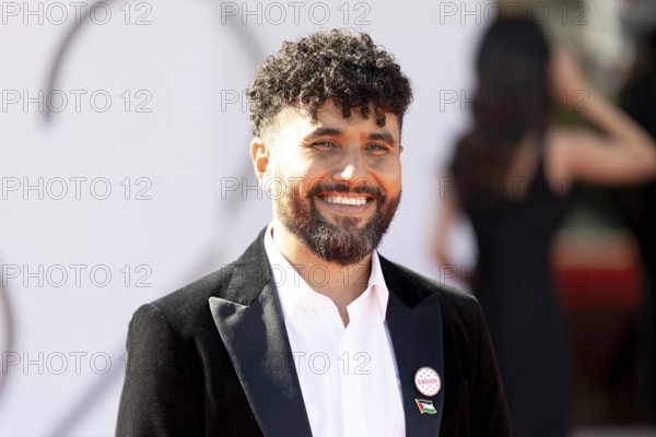 Venice, Italy - 3 September 2025: Amine Bouhafa wears a sticker in the colours of the Palestine flag and a sticker with the inscription - enough - on his jacket during the red carpet of - The Voice Of Hind Rajab - during the 82nd Venice International Film Festival