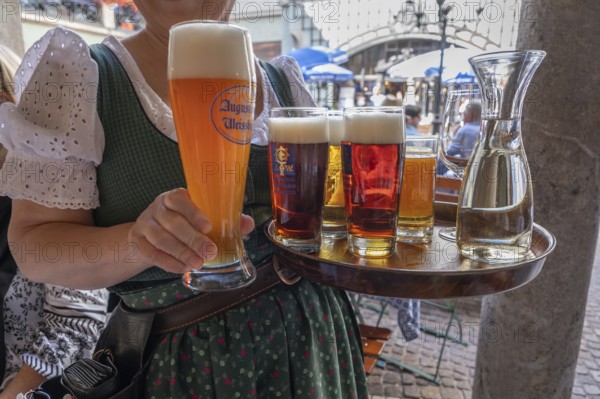 Drinks on a tray are served by a waitress in the beer garden, Munich, Bavaria, Germany