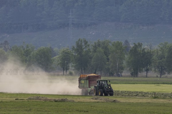 Tractor driving with trailer, mowing grass, meadow, dust, drought, summer, Alpine foothills, Bad-Tölz district, Bavaria, Germany