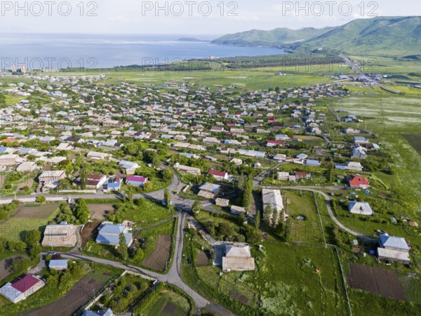 A bird's eye view of a village with scattered houses and green landscape near the coast, aerial view, Tsovagyugh, Lake Sevan, Gegharkunik Province, Armenia