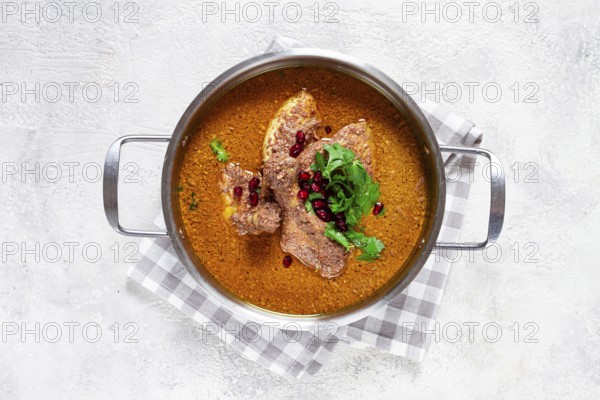 Fesenjan, an Iranian dish, stewed chicken, in a nut-pomegranate sauce, in a saucepan, light background, homemade, no people