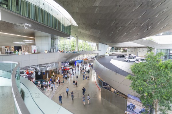 Large, modern showroom with visitors and various cars, BMW Welt, Munich, Germany