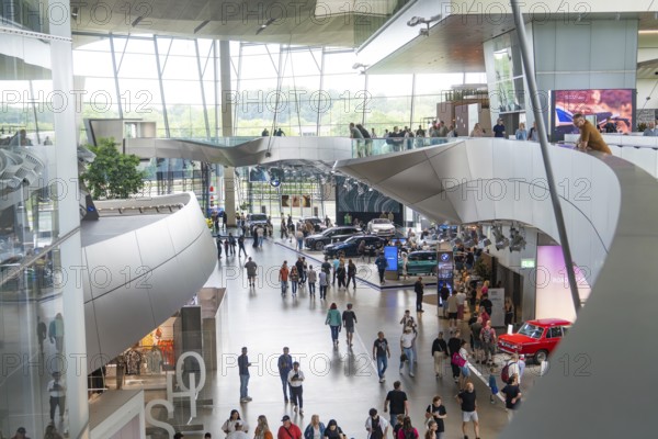 Modern interior with people and exhibited cars in a light-flooded environment, BMW Welt, Munich, Germany