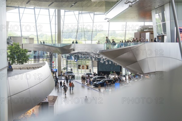 Interior with modern glass structure and people moving between cars, BMW Welt, Munich, Germany