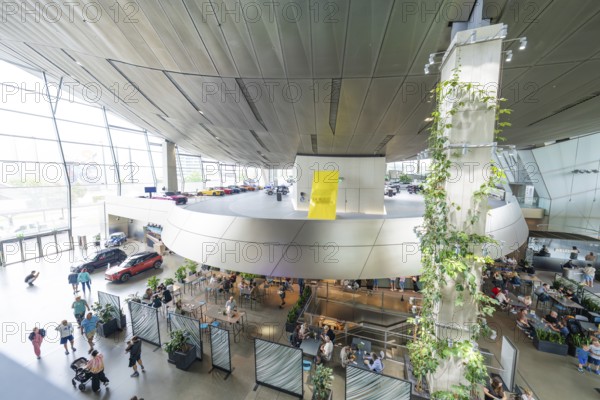Aerial view of a modern interior with a wall of plants and a crowd of people, BMW Welt, Munich, Germany