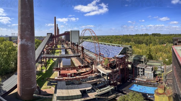 The Zollverein coking plant, on the right the works swimming pool, always in operation during the North Rhine-Westphalia summer holidays, former art object, now bathing fun against the backdrop of what was once the largest central coking plant in Europe, closed in 1993, part of the UNESC World Heritage Zollverein Coal Mine Industrial Complex, Essen, North Rhine-Westphalia, Germany
