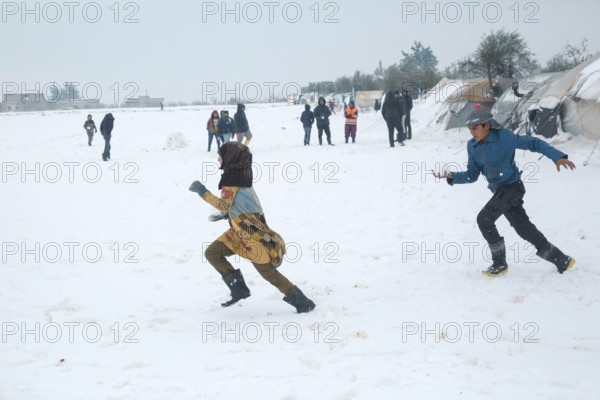 Displaced Syrian children playing in the snow near their tents inside a refugee camp during winter. Aleppo, Syria January 23, 2022, Aleppo, Syria