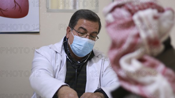 A Syrian doctor wearing a protective mask consults with a displaced patient inside a medical clinic. Aleppo, Syria May 28, 2022, Aleppo, Syria