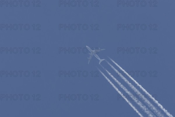 Airbus A340-300 jet aircraft of Lufthansa airlines in flight in a blue sky with vapour trails or contrails behind, England, United Kingdom