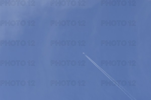 Boeing 737 jet passenger aircraft of Norweign Air with a vapour trial or contrail behind flying in a blue sky, England, United Kingdom